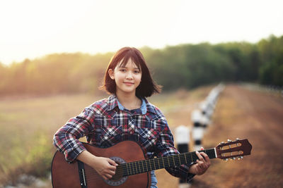 Portrait of young woman playing guitar