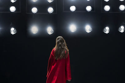 Rear view of woman standing against illuminated lights