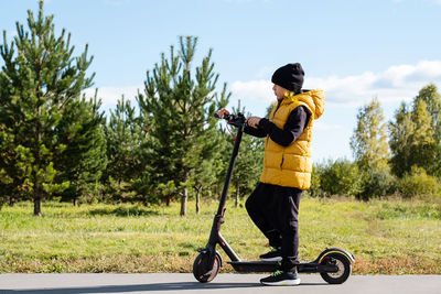 Boy rides an electric scooter in autumn park. schoolboy using e-scooter at sunny day.