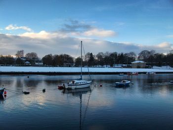 Sailboats moored on lake against sky