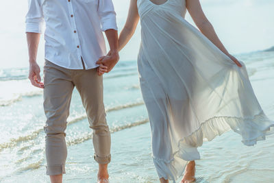 Couple holding hands while walking at shore