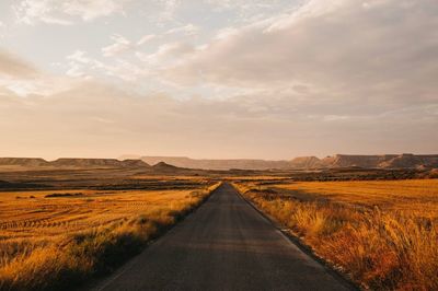 Road passing through land against sky