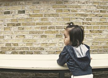 Full length of woman standing against brick wall