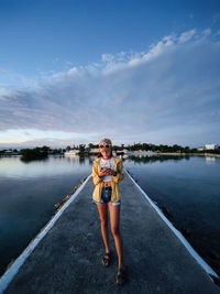 Full length of woman with arms raised against sky