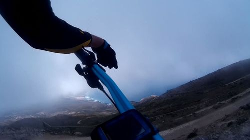 Man with arms raised against sky