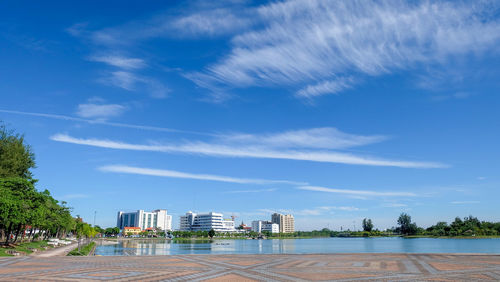 Buildings by river against blue sky