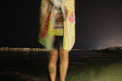 Low section of woman standing in water at night