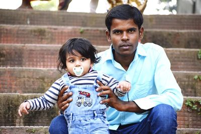 Portrait of father and daughter sitting outdoors