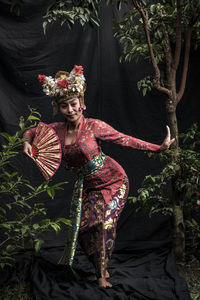 Woman in traditional clothing holding hand fan while dancing