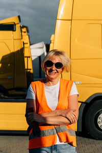 Portrait of driver with arms crossed in front of truck