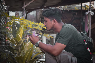 Side view of young man looking at flowering plants