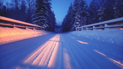 Road amidst trees against blue sky during winter