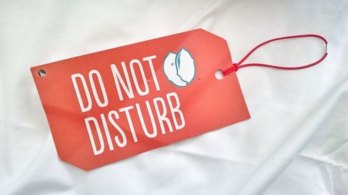 Do not disturb sign on hotel bed relaxing and leisure time , travel , vacation , holiday summertime