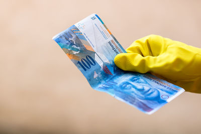 Close-up of a hand holding yellow paper over blue background