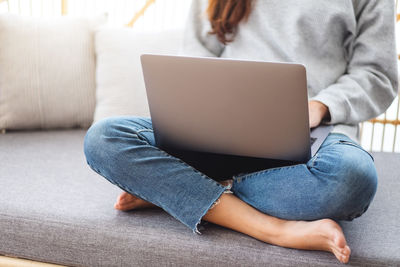 Low section of woman using laptop at home