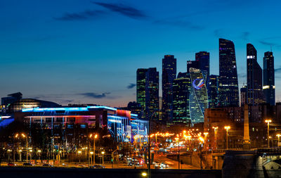 Illuminated buildings against blue sky at night