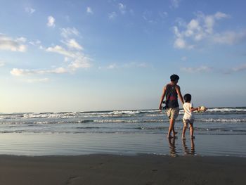 Father and daughter on beach against sky