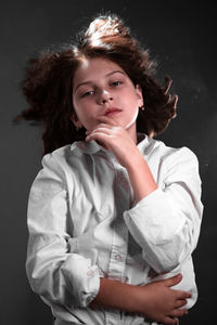 Portrait of teenage girl looking away against black background