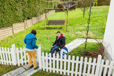 High angle view of woman opening gate for man sitting on wheelchair