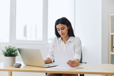 Young woman using laptop at desk in office