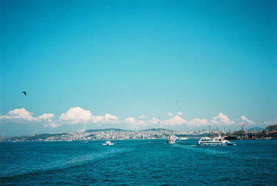 Sailboats sailing in sea against blue sky