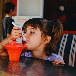 Girl holding ice cream on table