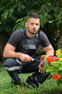 Full length of young man holding flowering plants