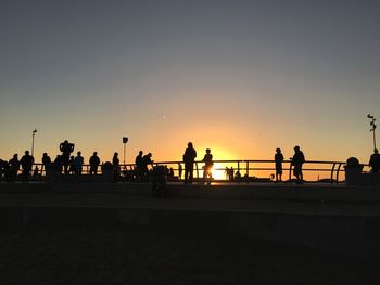 Silhouette people at venice skate park against sky during sunset