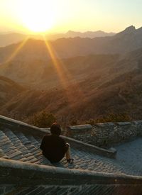 Rear view of man on mountain against sky during sunset