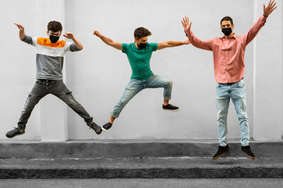 Full length of young man jumping against wall