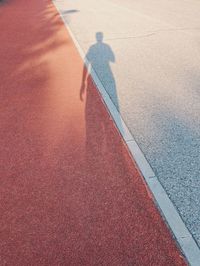 Long shadow of person walking on runway and road