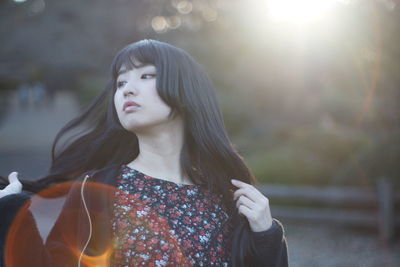 Young woman looking away while standing outdoors
