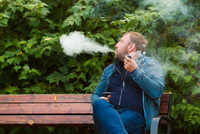 Man smoking pipe while sitting on bench