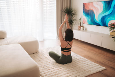 Rear view of woman sitting on sofa at home