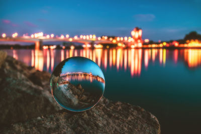 Close-up of crystal ball on rock against river at night