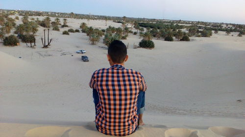 Rear view of man sitting in desert