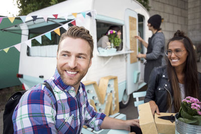 Happy customers sitting at table while food truck owners working in background