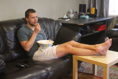 Young man sitting on sofa at home