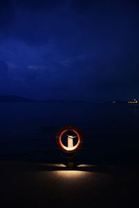 Illuminated light on beach against sky at night