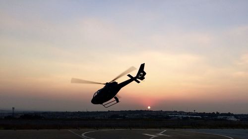 Airplane flying in sky at sunset