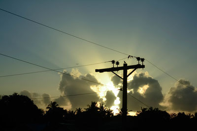 Low angle view of silhouette electricity pylon against sky during sunset