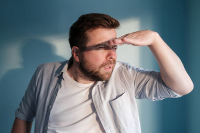 Portrait of young man standing against blue background