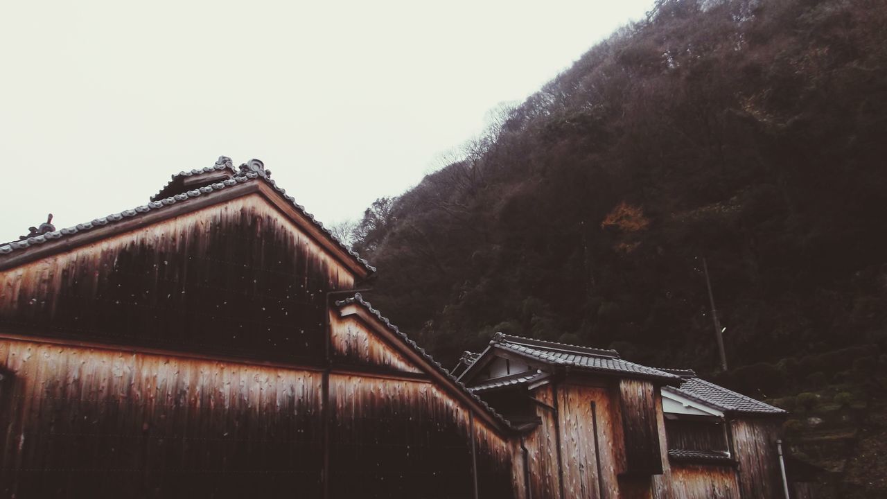 built structure, architecture, building exterior, house, clear sky, roof, mountain, residential structure, tree, copy space, wood - material, residential building, sky, old, day, outdoors, low angle view, abandoned, no people, nature