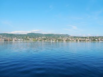 Scenic view of sea by town against blue sky