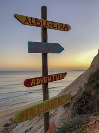 Sign board on beach against sky