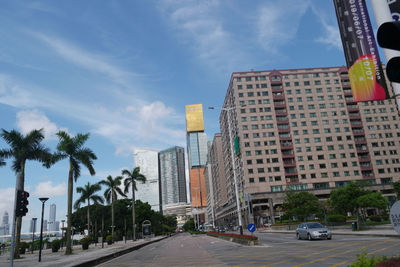 Road by buildings in city against sky