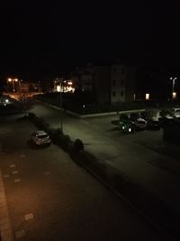 Cars on city street by buildings at night