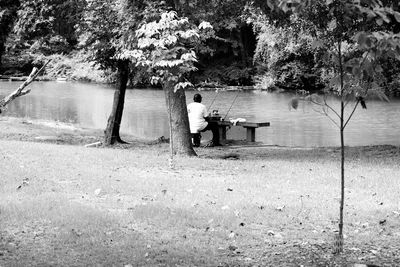 Man sitting on tree by water