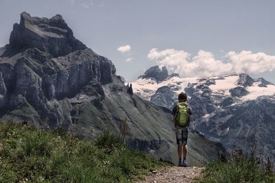 Rear view of man walking on mountain against sky