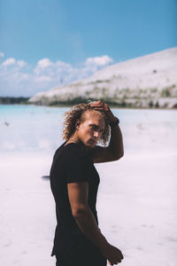 Side view of man standing at beach against sky